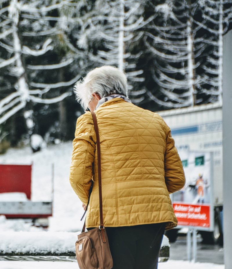 Eldre kvinne går ute om vinteren